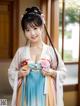 A woman in a blue and pink hanbok is posing for a picture.