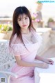 A woman in a pink dress sitting on a white chair.