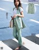 A woman in a green suit is standing on the street.