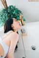 A woman in a bathtub with a plant in the background.