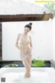 A naked woman standing in a bathtub with foam on her body.