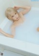 A woman laying in a bathtub with her hands behind her head.