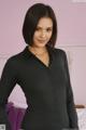 A woman in a black shirt posing on a bed.