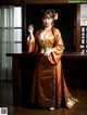 A woman in an orange kimono posing for a picture.