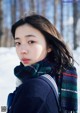 A woman wearing a scarf standing in the snow.