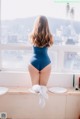 A woman in a blue bodysuit sitting on a window sill.