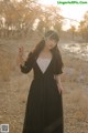 A woman in a black dress standing in a field.