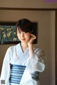 A woman in a blue and white kimono posing for a picture.