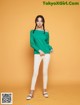 a woman in a green top and white pants posing for a picture