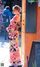 A woman in a kimono standing in front of a door.