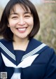 A woman in a sailor outfit smiles at the camera.