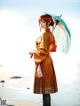 A woman in a kimono holding an umbrella on the beach.