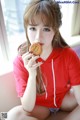 A woman sitting on a couch eating a cookie.