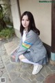 A young woman sitting on the ground holding a magazine.