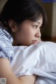 A woman laying in bed with her head on a pillow.