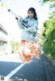 A woman in a blue sweatshirt and orange skirt holding a telescope.