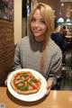 A woman holding a plate with a pizza on it.